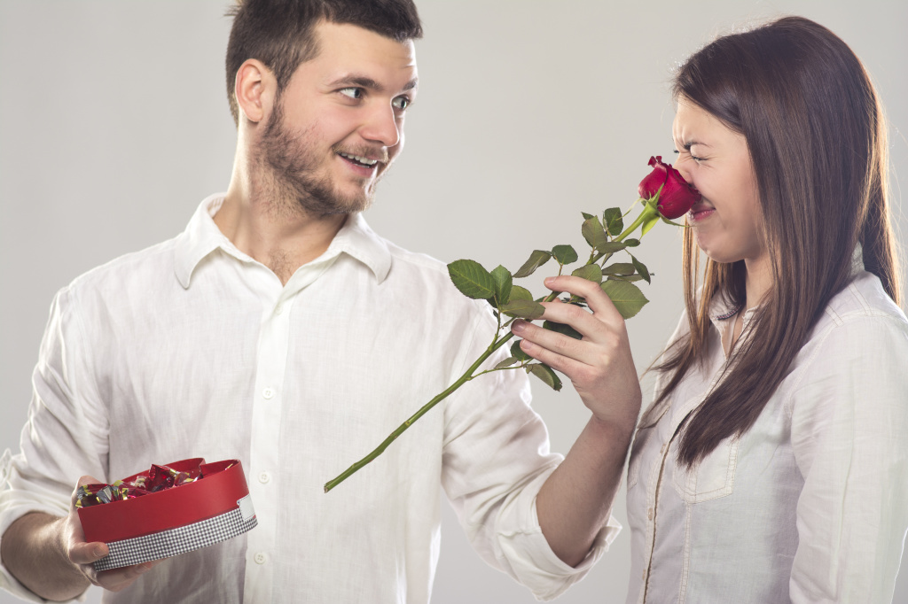 Young man putting rose on girlfriend’s nose